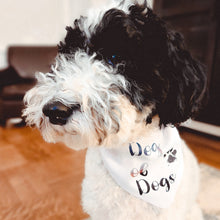 Load image into Gallery viewer, Cute and fluffy black and white doodle wearing white bandana with multi-colored writing and muddy paw print which reads &quot;dog of dogs&quot;
