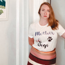 Load image into Gallery viewer, woman standing wearing a mother of dogs tshirt with multi-colored writing which reads &quot;Mother of dogs&quot; with a muddy paw print inspired by game of thrones 
